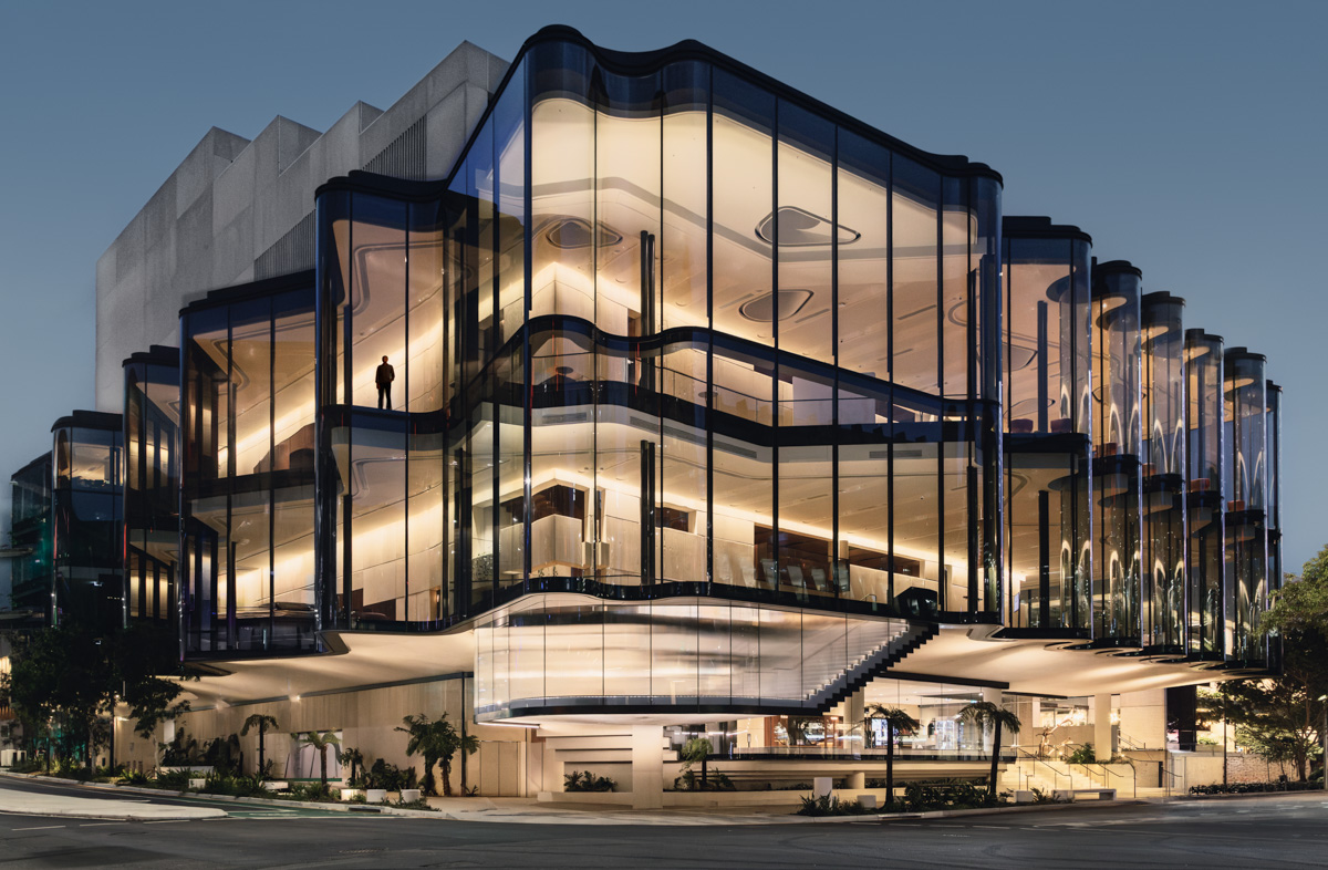 Illuminated curved glass facade at blue hour — Glasshouse Theatre